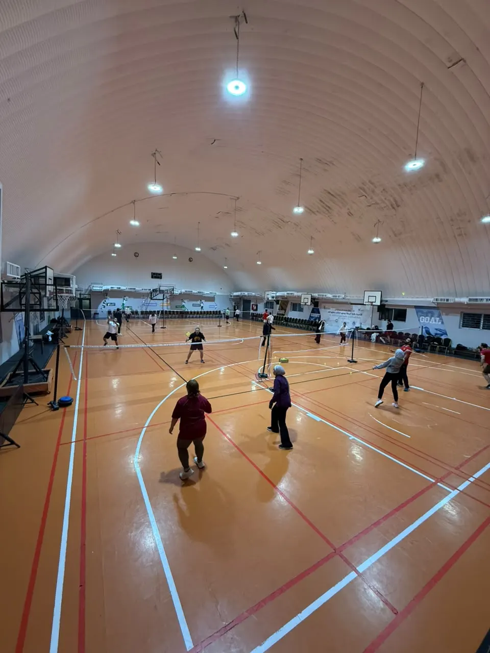 لاعبون يتدربون على عدة ملاعب داخل صالة دوبامين للريشة الطائرة